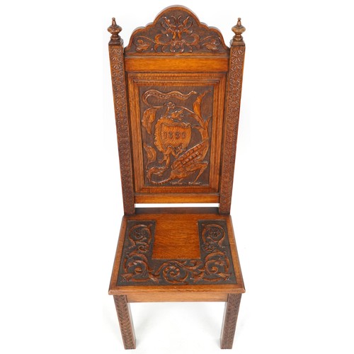 1035 - Victorian oak hall chair heavily carved with a dragon and shield, dated 1898, 120cm high