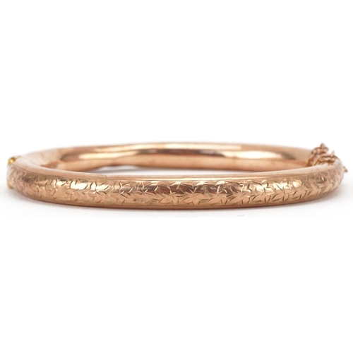 3050 - George V 9ct rose gold hinged bangle engraved with foliage, 7cm wide, 9.4g