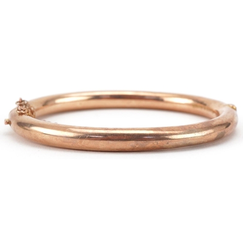 3050 - George V 9ct rose gold hinged bangle engraved with foliage, 7cm wide, 9.4g