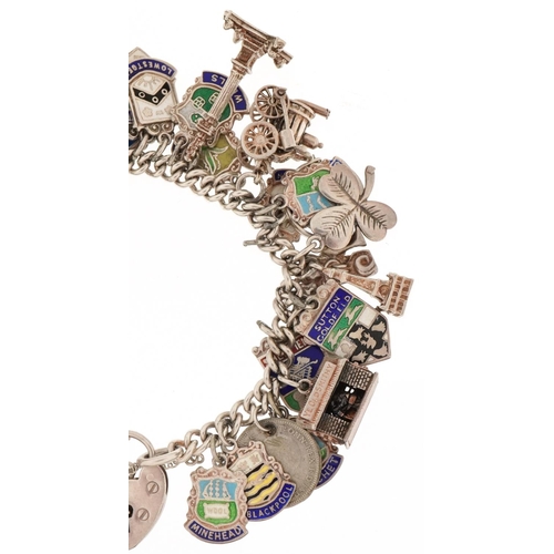 3131 - Silver charm bracelet with a large collection of mostly silver charms including enamelled shield sou... 