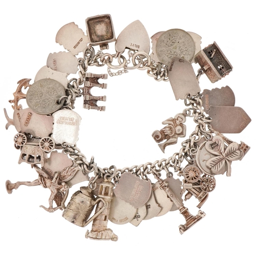 3131 - Silver charm bracelet with a large collection of mostly silver charms including enamelled shield sou... 