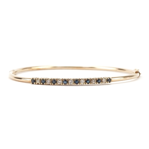 3005 - 9ct gold diamond and sapphire hinged bangle set with seven diamonds and eight sapphires, 6.5cm wide,... 