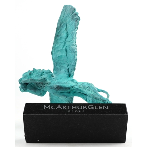 526 - Mark Coreth for McArthur Glen Group, verdigris bronze figure of a winged lion raised on a black slat... 