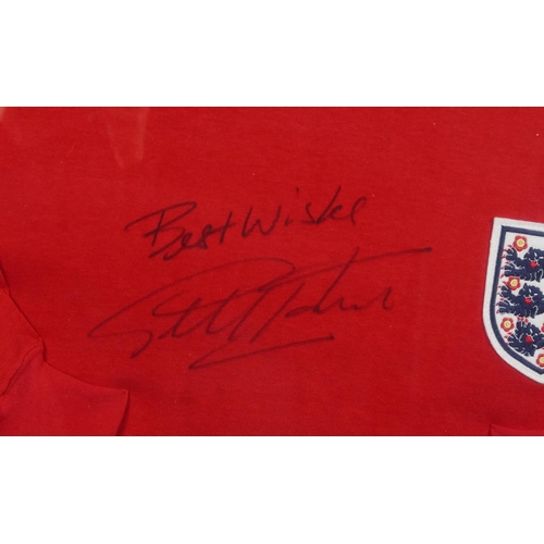 2486 - Signed replica England jumper by Sir Geoff Hurst, framed and glazed, 87cm x 62cm, together with a Wo... 