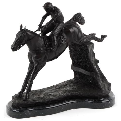 268 - Patinated bronze study of a jockey on horseback jumping a fence, raised on a black marble base, 35cm... 