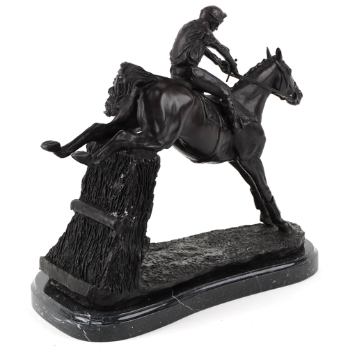 268 - Patinated bronze study of a jockey on horseback jumping a fence, raised on a black marble base, 35cm... 