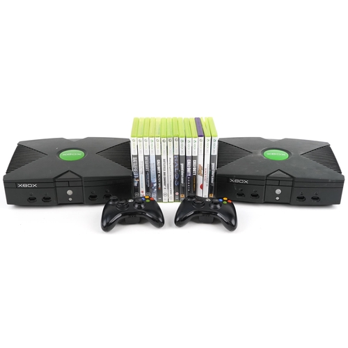 2073 - Two Xbox games consoles with two Xbox controllers and a collection of Xbox 360 games