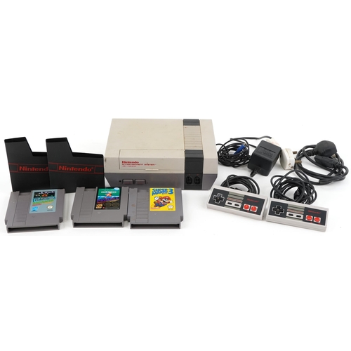 2065 - Nintendo NES version entertainment system with games and controllers, model number NESE-001