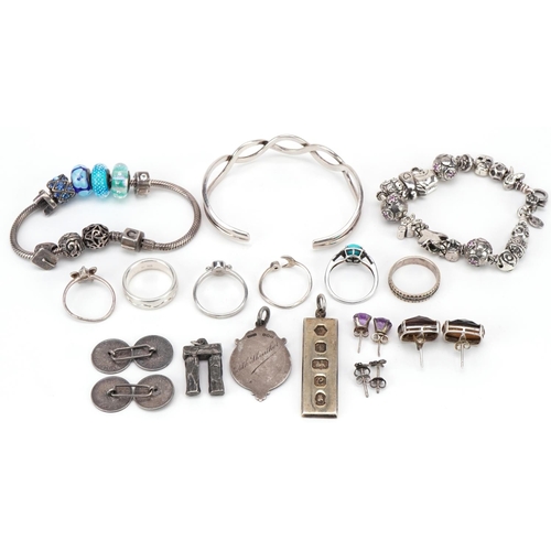 3165 - Silver and white metal jewellery including two charm bracelets, silver ingot pendant, sports jewel, ... 