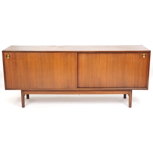 1058 - Mid 20th century teak sideboard, the sliding doors revealing sliding trays to one end, raised on tur... 