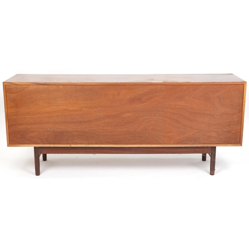 1058 - Mid 20th century teak sideboard, the sliding doors revealing sliding trays to one end, raised on tur... 