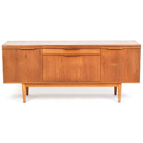 1001 - Mid 20th century teak sideboard, the central door and fall flap flanked by two cupboards on tapering... 