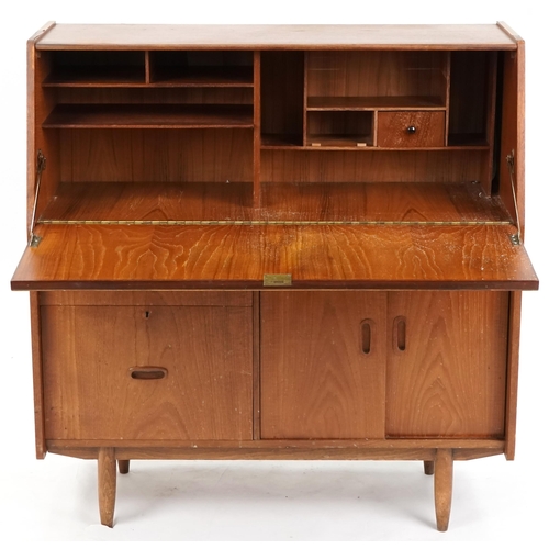 1057 - Mid to late 20th century teak bureau, the fall flap above two drawers and a cupboard on tapering leg... 