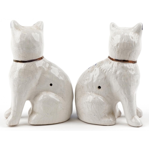 1357 - A pair of early 20th century Staffordshire pottery  white glazed seated cats, each decorated with bl... 