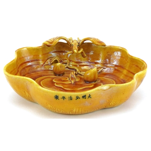 151 - A Chinese porcelain yellow glazed brush washer relief decorated with a bat and fruit, 16cm wide.