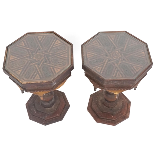 1035 - A pair of Eastern carved softwood octagonal lamp tables raised on turned supports and platform bases... 