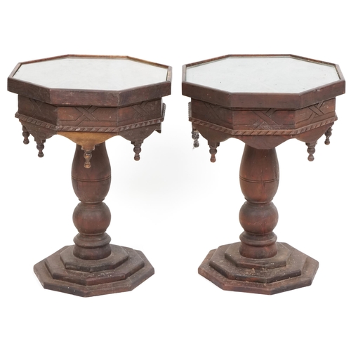 1035 - A pair of Eastern carved softwood octagonal lamp tables raised on turned supports and platform bases... 