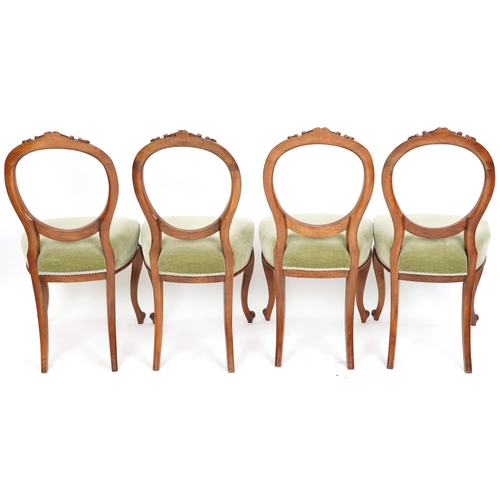 1073 - A set of four Victorian walnut balloon back dining chairs, the overstuffed seats upholstered in gree... 