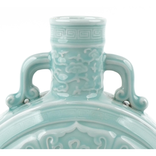 45 - A Chinese porcelain celadon glazed moon flask with twin handles relief decorated with foliage and ob... 