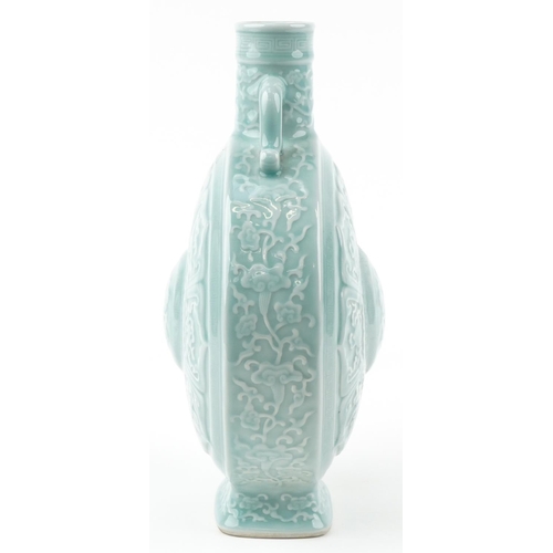 45 - A Chinese porcelain celadon glazed moon flask with twin handles relief decorated with foliage and ob... 