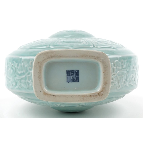 45 - A Chinese porcelain celadon glazed moon flask with twin handles relief decorated with foliage and ob... 