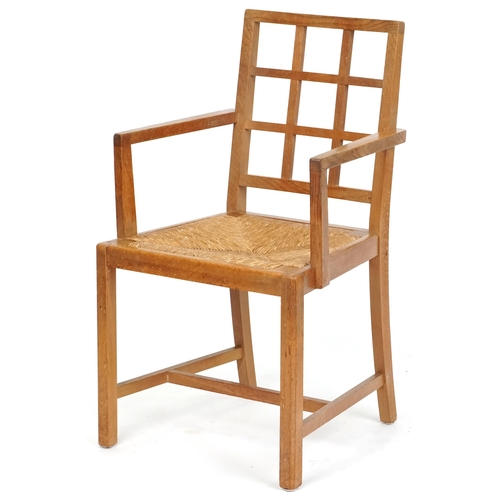 1132 - A 20th century oak lattice back elbow chair with rush seat, 91cm high x 52cm wide.