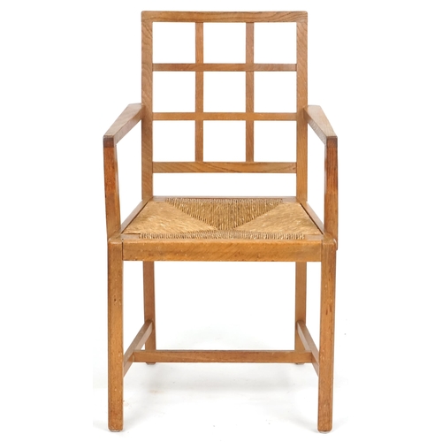 1132 - A 20th century oak lattice back elbow chair with rush seat, 91cm high x 52cm wide.