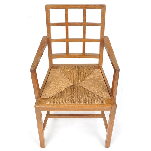 1132 - A 20th century oak lattice back elbow chair with rush seat, 91cm high x 52cm wide.