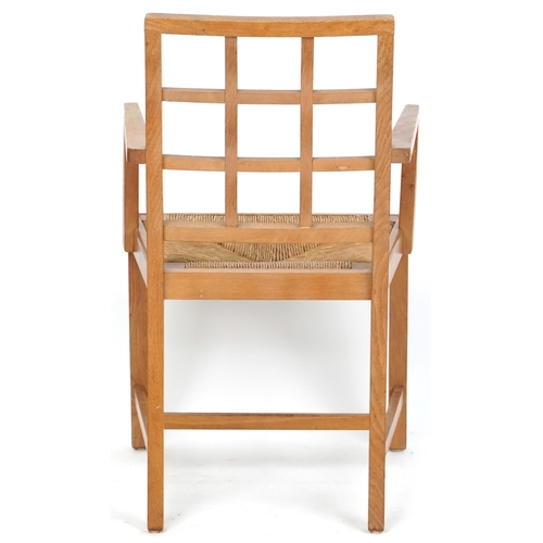 1132 - A 20th century oak lattice back elbow chair with rush seat, 91cm high x 52cm wide.