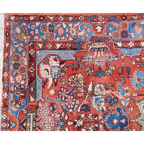 1061 - A Heriz carpet, late 20th century, the red field with a central medallion flanked by complementary b... 