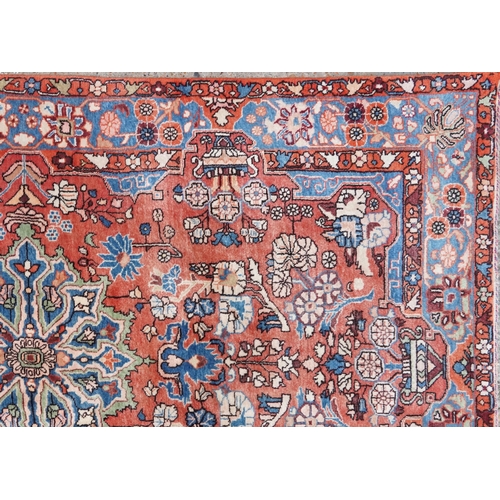 1061 - A Heriz carpet, late 20th century, the red field with a central medallion flanked by complementary b... 