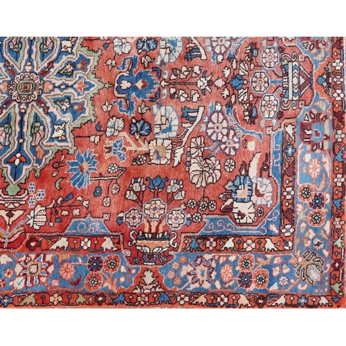 1061 - A Heriz carpet, late 20th century, the red field with a central medallion flanked by complementary b... 