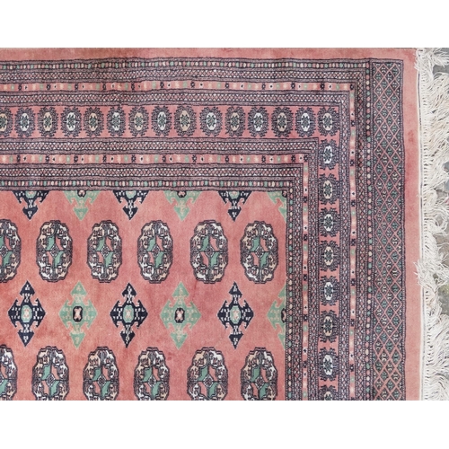 1060 - A Tekke carpet, late 20th century, the salmon field with three rows of guls flanked by a complementa... 