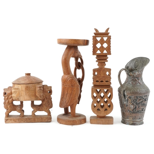 1458 - Three carved wooden statues and a copper jug decorated with animals and figures on horseback, the la... 