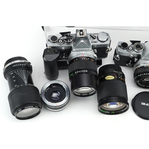 521 - A collection of cameras with lenses including Olympus OM-1, Olympus OM-2, 28-80mm and 70-210mm.