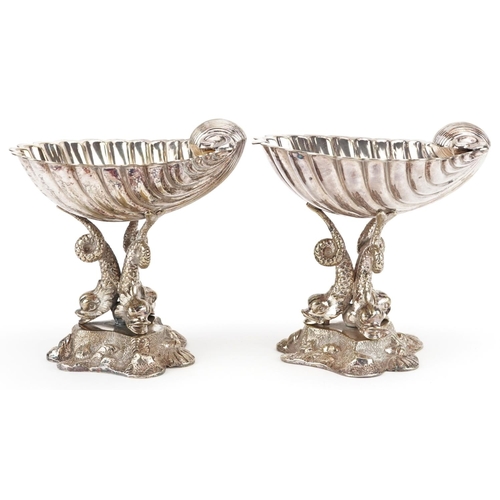 1358 - A pair of late 19th century plated bonbon dishes, the half shell bowl raised on three dolphin suppor... 