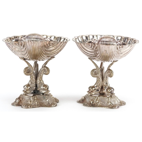 1358 - A pair of late 19th century plated bonbon dishes, the half shell bowl raised on three dolphin suppor... 