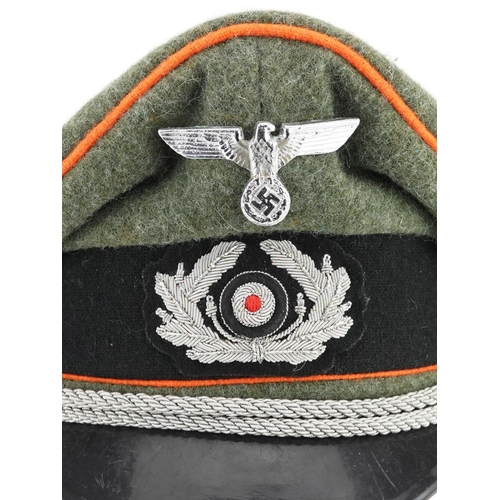 2594 - A German military interest visor cap with insignia.