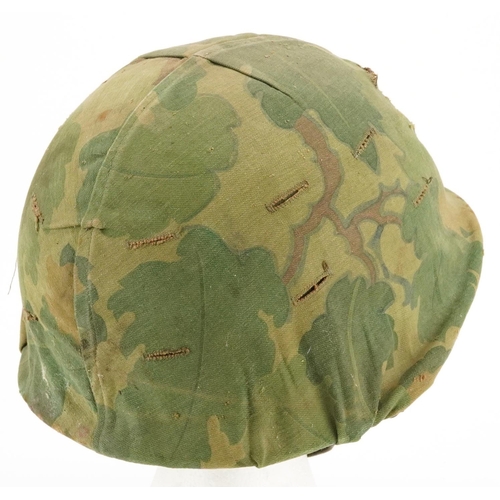 2599 - A military interest tin helmet with camo cover, liner and chin strap.