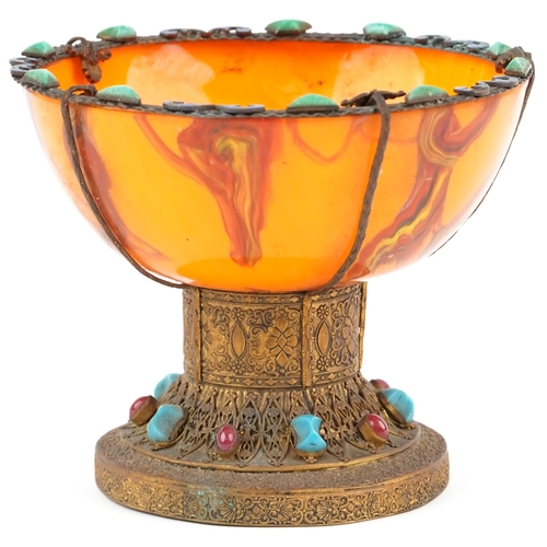 326 - A Tibetan gilt metal tazza with embossed decoration, 20th century, the later orange glass bowl fitte... 