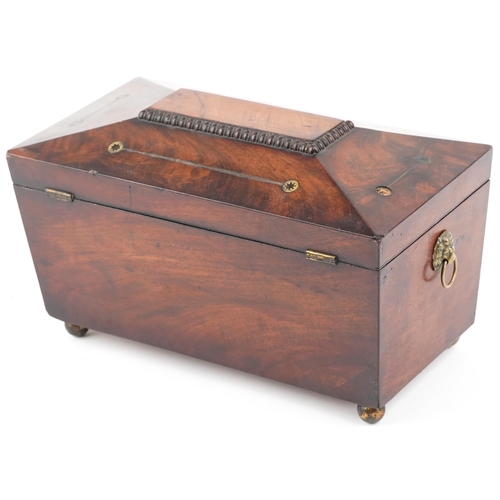 142 - An early 19th century figured mahogany sarcophagus tea caddy with brass inlaid decoration, the hinge... 