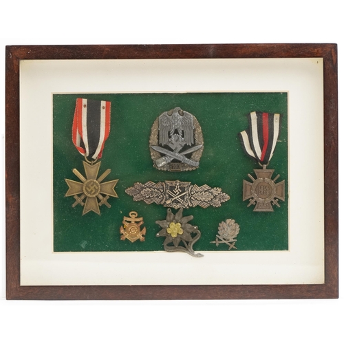 2544 - Five German military interest cap badges and two medals, framed and glazed.