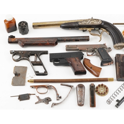 2606A - A collection of military interest gun parts, starting pistol and a decorative percussion pistol.