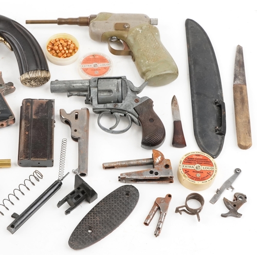 2606A - A collection of military interest gun parts, starting pistol and a decorative percussion pistol.