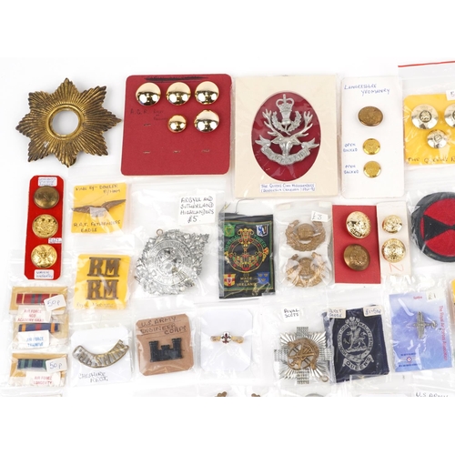 2470 - A large collection of militaria, cap badges, shoulder titles and collar badges including Machine Gun... 