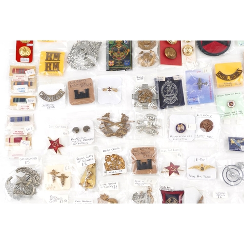 2470 - A large collection of militaria, cap badges, shoulder titles and collar badges including Machine Gun... 