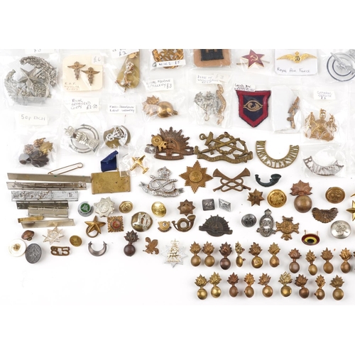 2470 - A large collection of militaria, cap badges, shoulder titles and collar badges including Machine Gun... 