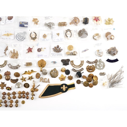 2470 - A large collection of militaria, cap badges, shoulder titles and collar badges including Machine Gun... 