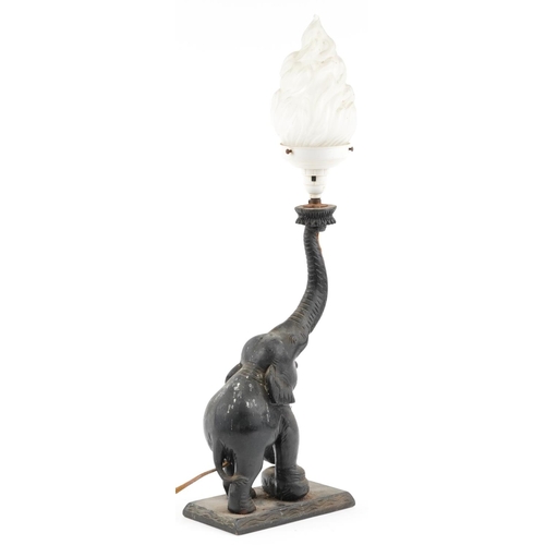 1341 - Ebonised carved wood table lamp in the form of an elephant with a frosted flame glass shade, 68cm hi... 