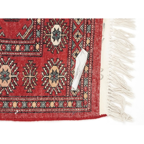 1033 - An Afghan runner, late 20th century, the red field with a two central rows of guls flanked by a comp... 